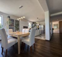 Interior of a family house with a dining room, kitchen, and wooden decor flooring.