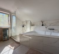 A bathroom in a family house with a bathtub and a shower, surrounded by tiles.