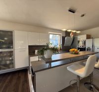 A kitchen in a family house with a bar counter and a wooden decor floor.