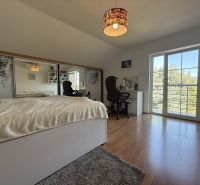 A bedroom with a simple headboard, a desk, and a wooden decor floor.