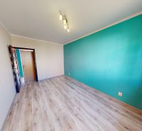 A room with a turquoise wall, a large window, and a wooden decor floor in a 3-room apartment.