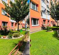 A garden with a bench and flowers in front of an apartment building on Tkáčska Street in Spišská Nová Ves.