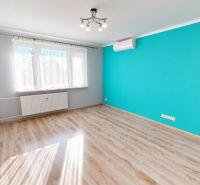 A room in a 3-room apartment with a blue wall and a wooden decor floor.