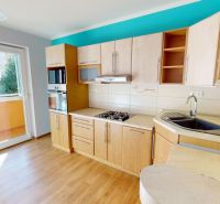 A kitchen in a 3-room apartment with a wooden decor floor and direct access to the balcony.