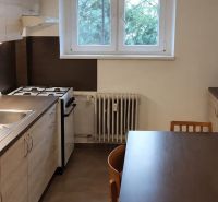 A kitchen in a studio apartment with a gas stove and a microwave on a dark countertop.