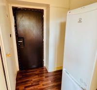 Interior with a refrigerator and a wooden decor floor in a studio apartment.