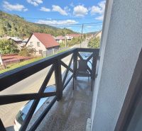 A balcony with a view of Centrum Street in Oščadnica, surrounded by greenery and houses, 1-room apartment.
