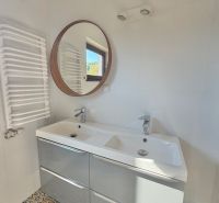 The bathroom in the studio apartment includes a double sink, a round mirror, and patterned tiles.