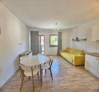 1-bedroom apartment with wood-patterned flooring, yellow sofa, and white furniture.
