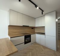 A kitchen in a 4-room apartment with a wooden decor floor and modern cabinets.