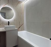 A bathroom with a rectangular bathtub and a round mirror in a 4-room apartment.