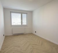 A room with a wooden decor floor in a 4-room apartment elegantly illuminated by a large window.