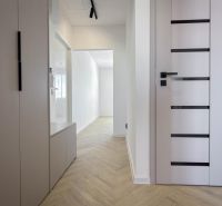 A hallway in a 4-room apartment with a floor and white doors.