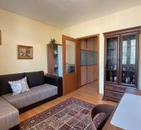 Living room in a 3-room apartment with furniture, wood-patterned flooring, and decorations.