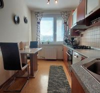 A kitchen in a 3-room apartment with a dining table and a wooden decor floor.