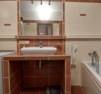 A bathroom in a 3-room apartment with a bathtub, sink, and washing machine.