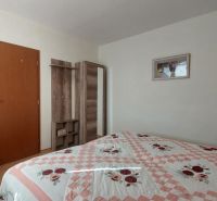 Bedroom with a bed, light wall, wooden wardrobe, and floor with wooden decor in a 3-room apartment.