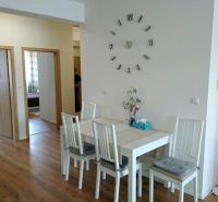 Dining room in a 3-room apartment with a wood-patterned floor and floral wallpaper.