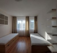 A room with two beds, shelves, and a floor with wooden decor in a three-room apartment.