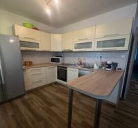A kitchen with light cabinets and a wood-patterned floor in a 2-room apartment.