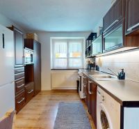 A kitchen in a 2-room apartment with a wooden decor floor and built-in appliances.