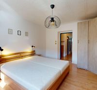 Bedroom with a double bed, wardrobe, and wooden decor flooring in a 2-room apartment.
