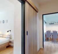 Bedroom with a bed, sliding doors, entrance to the dining room, and a floor with a wooden decor.