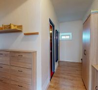 A hallway in a 2-room apartment with wooden decor furniture and coat racks.