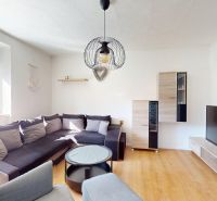 Living room in a two-room apartment with a wooden decor floor and a sofa set.