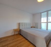 A bedroom in a 2-room apartment with a bed and a wooden decor floor.
