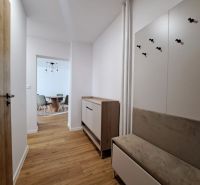 A hallway in a 2-room apartment with a wooden decor floor, hallway furniture, and a dining area.