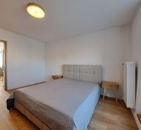Bedroom with a bed and nightstands, wooden decor flooring in a two-room apartment.