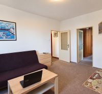 Living room in a 3-room apartment with a sofa, coffee table, and paintings on the wall.