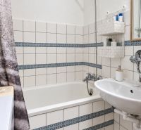 Bathroom with a bathtub, sink, white tiles, and patterned details in a 3-room apartment.