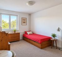 A bright room in a 3-room apartment with a bed, a table, and wooden elements.