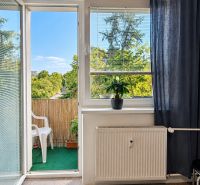 Living room in a three-room apartment with a view of the balcony and greenery.