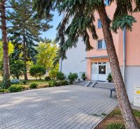Entrance to a 3-room apartment in Pezinok on Za hradbami Street, surrounded by greenery and paving.