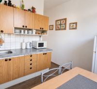 A kitchen in a 3-room apartment with a wood-patterned floor, white walls, and wooden cabinets.