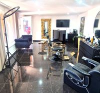 Hair salon with black granite flooring, large mirrors, and comfortable chairs.