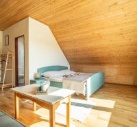 Attic room with a bed, table, and wooden decor flooring in a hotel.
