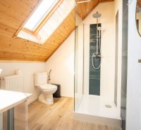 Attic bathroom with a sink, shower, and floor with wood decor.
