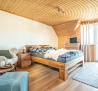 A hotel room with a bed, chair, carpet, and wooden decor flooring.