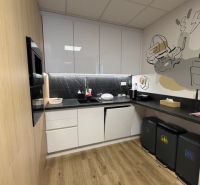 A kitchen in a building with a wooden decor floor and modern furniture.