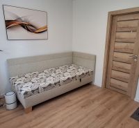 A room in a 3-room apartment with a wooden decor floor, a sofa, and an office chair.
