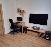 A workspace with a computer and television, wooden decor flooring in a 3-room apartment.
