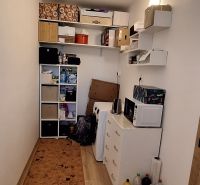 A compact room with shelves, a wardrobe, and a floor with a wooden decor in a 3-room apartment.