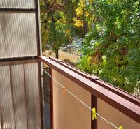 Balcony of a 3-room apartment in Komárno with a view of green trees.