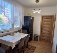 Dining area with a window, dark refrigerator, curtains, and a table in a 3-room apartment.