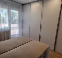 Bedroom in a 3-room apartment with a large wardrobe and a window with curtains.