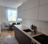 A kitchen in a 3-room apartment, with a wooden decor floor and a dining area.
